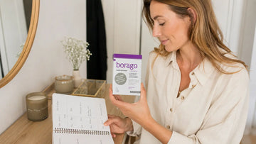 Adult woman holding Elexir Borago while reviewing her supplement routine